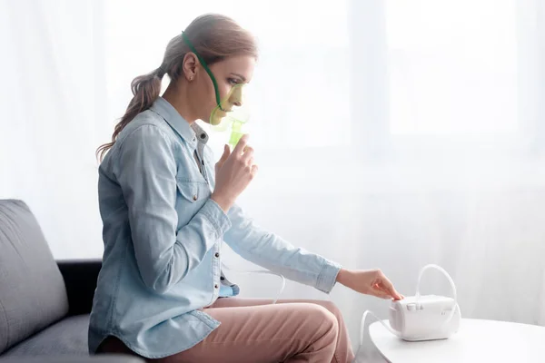 Vista lateral de la mujer en máscara respiratoria tocando el inhalador del compresor - foto de stock