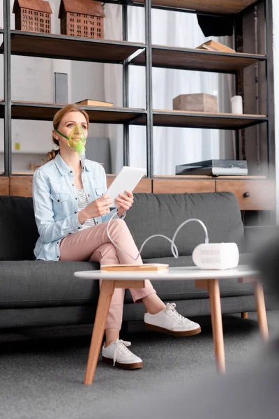 Selective focus of asthmatic woman using compressor inhaler and holding digital tablet — Stock Photo