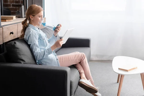 Side view of asthmatic woman using inhaler with spacer and holding digital tablet — Stock Photo