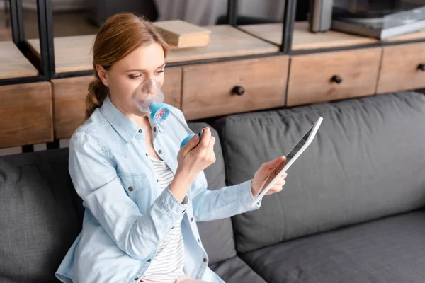 Asthmatic woman using inhaler with spacer and holding digital tablet — Stock Photo