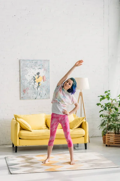 Girl with colorful hair warming up with hand on hip in living room — Stock Photo