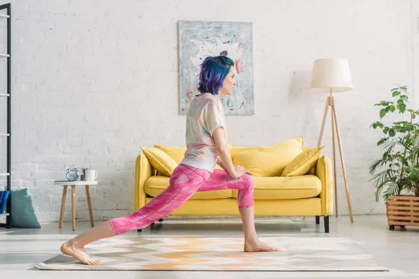 Frau mit bunten Haaren macht Yoga-Asana im Wohnzimmer — Stockfoto