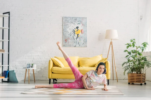 Chica con el pelo colorido estiramiento y mirando hacia el suelo en la sala de estar — Stock Photo