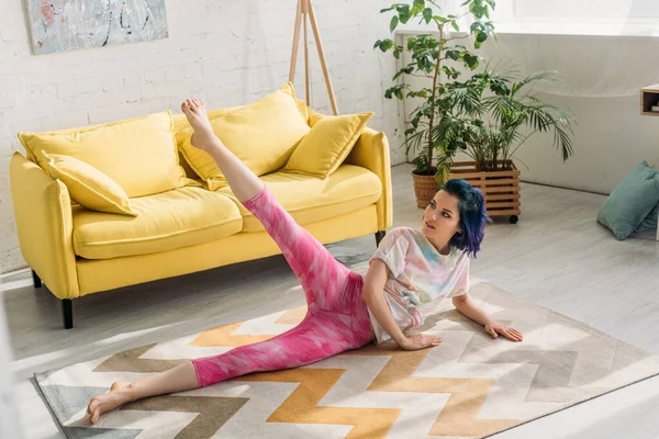 Hochwinkel-Ansicht von Mädchen mit bunten Haaren, die sich auf dem Boden im Wohnzimmer strecken — Stockfoto