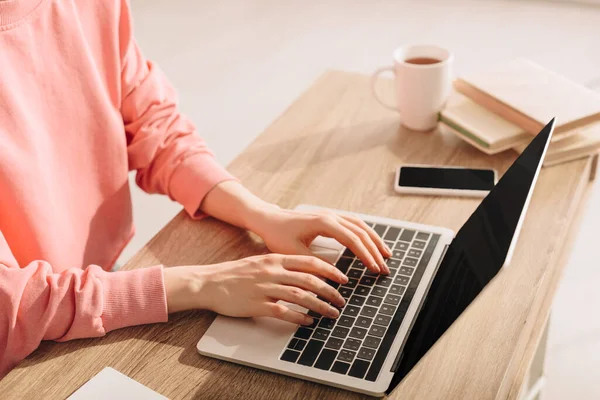 Vista recortada del freelancer trabajando con portátil en la mesa - foto de stock