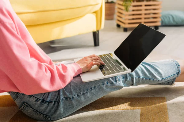 Vista ritagliata di freelance che lavora con il computer portatile e si siede sul pavimento in soggiorno — Foto stock