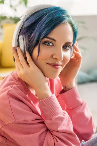 Hermosa mujer con pelo colorido y auriculares escuchando música, mirando a la cámara y sonriendo - foto de stock