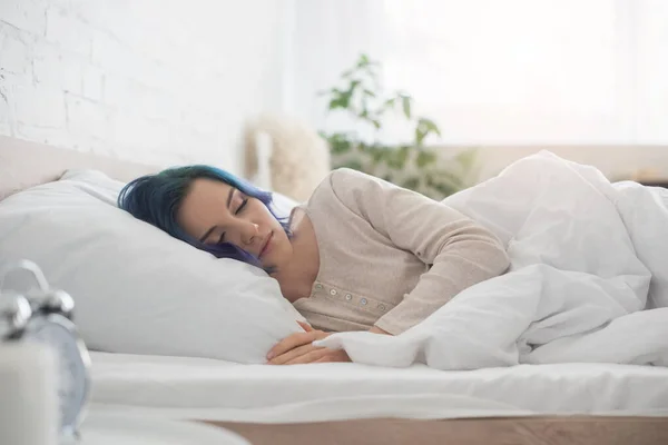 Selektiver Fokus der Frau mit bunten Haaren, die auf dem Bett im Schlafzimmer schläft — Stockfoto