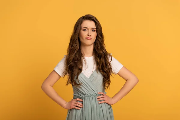 Beautiful skeptical spring woman in dress isolated on yellow — Stock Photo