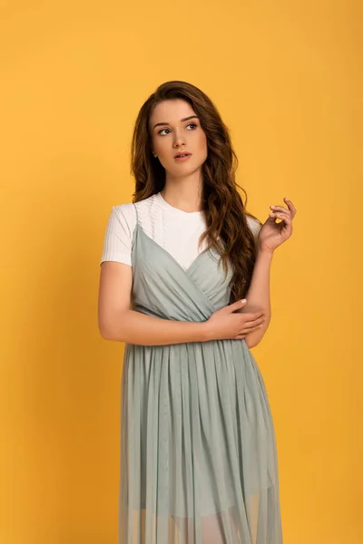 Attractive thoughtful girl in t-shirt and dress on yellow — Stock Photo