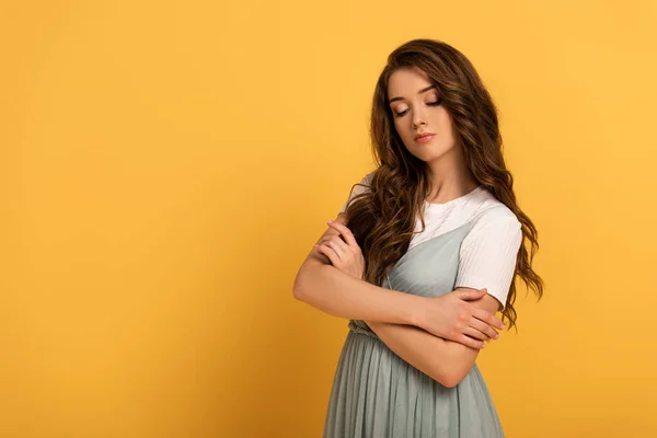 Atractiva chica tierna con brazos cruzados en amarillo - foto de stock