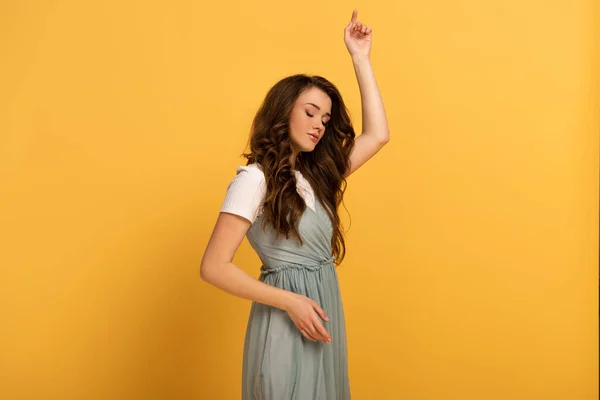 Tender young spring woman dancing in elegant dress on yellow — Stock Photo