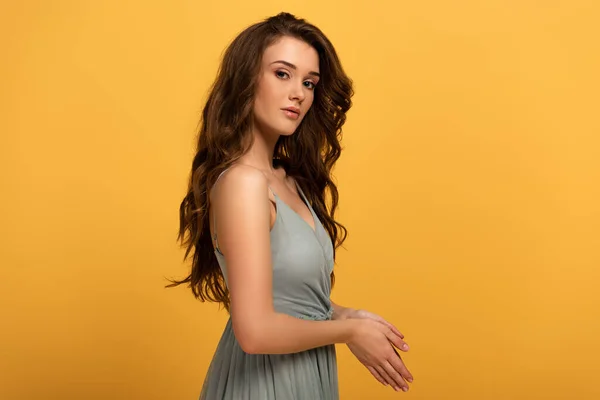 Attractive spring girl with long hair in dress isolated on yellow — Stock Photo