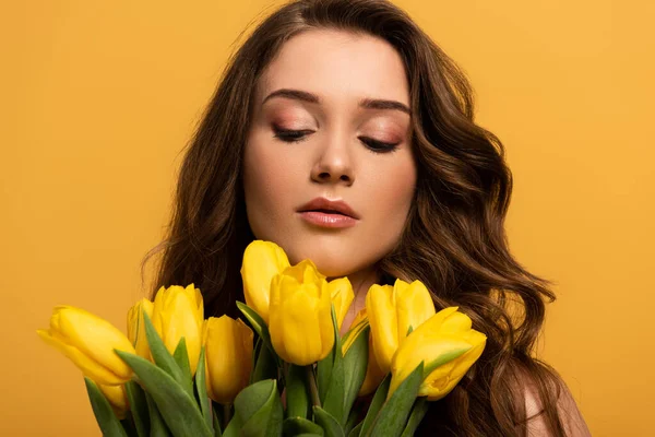 Menina macia com maquiagem segurando buquê de flores de tulipa isolado no amarelo — Fotografia de Stock