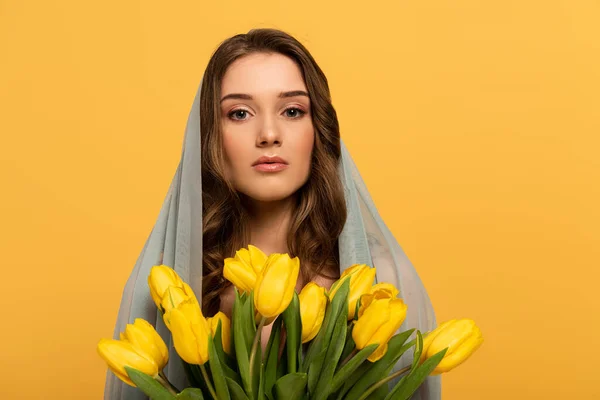 Attractive young woman in veil holding bouquet of tulips isolated on yellow — Stock Photo