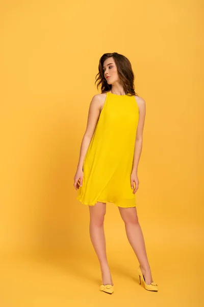 Attractive elegant young woman in dress on yellow — Stock Photo
