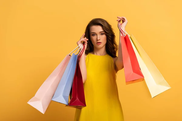 Bella ragazza elegante in abito primavera che tiene borse della spesa su giallo — Foto stock