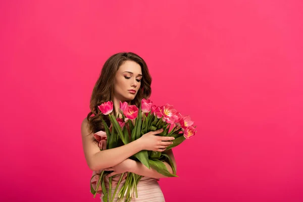 Bonita chica sosteniendo ramo de flores de tulipán de primavera aislado en rosa - foto de stock