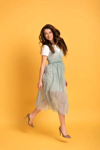 Happy spring girl jumping in t-shirt and dress on yellow — Stock Photo