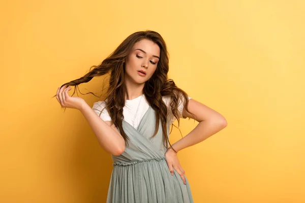 Nachdenkliche junge Frühlingsfrau mit langen Haaren auf gelb — Stockfoto