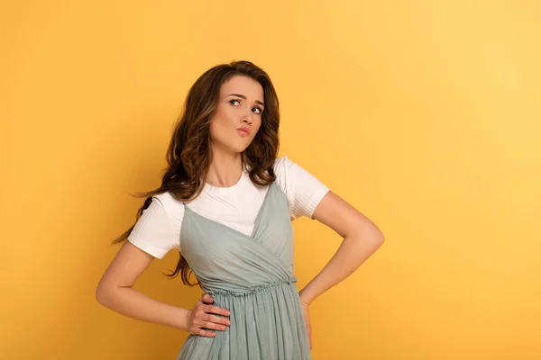 Attractive confused spring girl in t-shirt and dress on yellow — Stock Photo