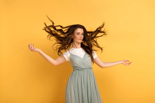 Sorridente giovane donna primaverile con i capelli lunghi su giallo — Foto stock