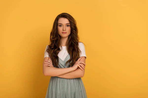 Attractive confident spring woman with crossed arms on yellow — Stock Photo