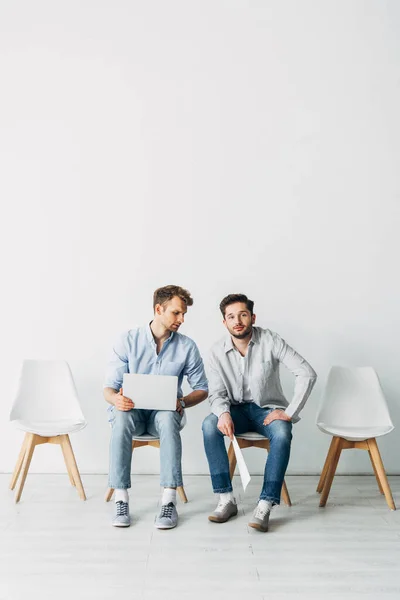 Schöner Mann mit Lebenslauf sitzt neben Mitarbeiter mit Laptop im Büro — Stockfoto