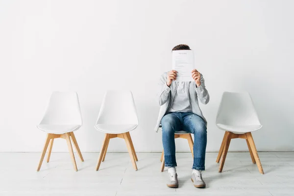 Kandidat verdeckt Gesicht mit Lebenslauf, während er auf Vorstellungsgespräch im Büro wartet — Stockfoto