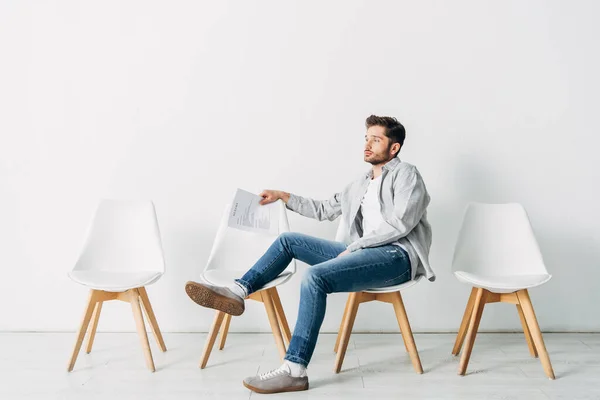 Вид сбоку человека с резюме, сидящего на стуле в офисе — стоковое фото