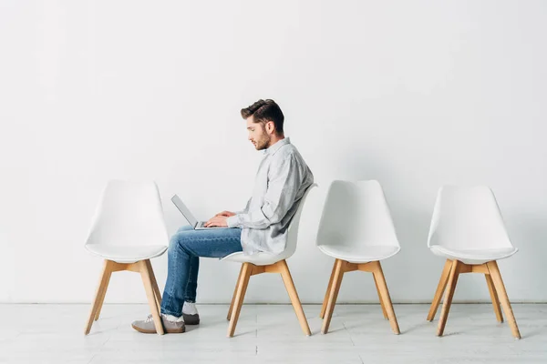 Vista laterale del candidato utilizzando il computer portatile sulla sedia in ufficio — Foto stock