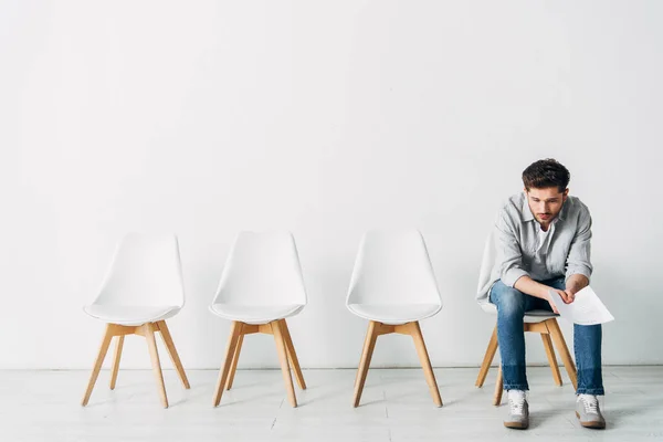 Hombre con curriculum vitae sentado en la silla en la oficina - foto de stock