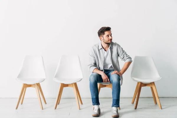 Beau employé regardant ailleurs tout en étant assis sur la chaise dans le bureau — Photo de stock