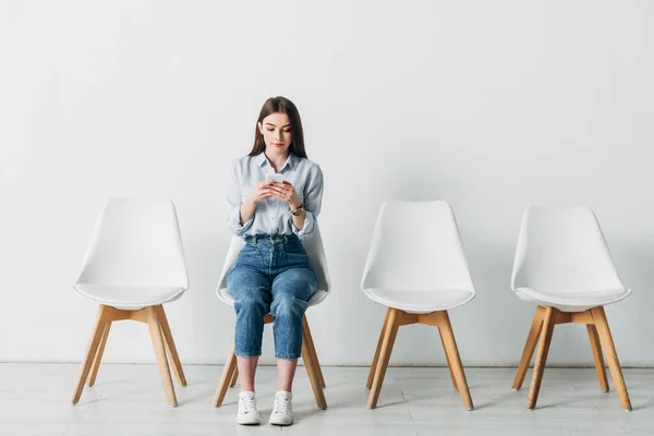 Giovane donna che utilizza smartphone in attesa di un colloquio di lavoro in ufficio — Foto stock