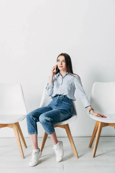 Attraktiver Mitarbeiter, der im Büro auf dem Stuhl sitzt und mit dem Smartphone spricht — Stockfoto