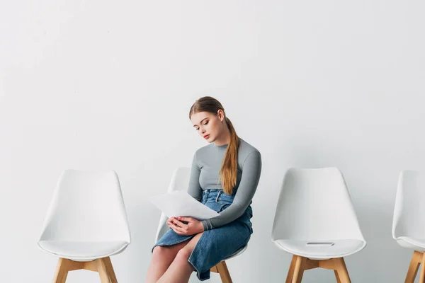 Mujer atractiva sosteniendo curriculum vitae mientras espera entrevista de trabajo en la oficina - foto de stock