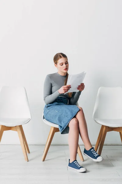 Jovem atraente leitura currículo enquanto espera por entrevista de emprego — Fotografia de Stock