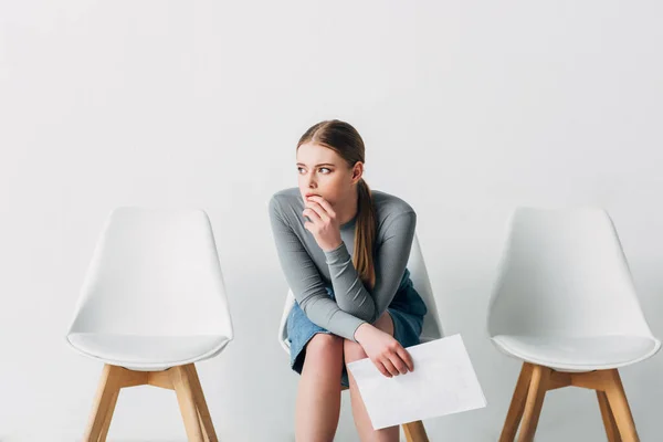 Nachdenkliche Frau mit Lebenslauf auf Stuhl im Büro — Stockfoto