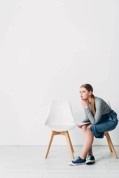 Vue latérale de la femme avec CV regardant loin sur la chaise dans le bureau — Photo de stock