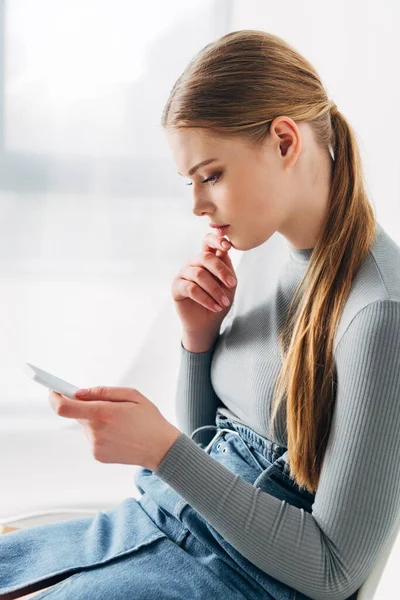 Side view of pensive candidate using smartphone while waiting for job interview in office — Stock Photo