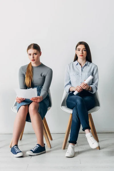 Attractive employees with resume looking at camera on chairs in office — Stock Photo