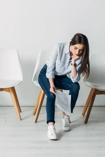 Pensive woman looking at resume while waiting for job interview in office — Stock Photo