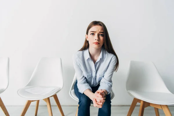 Stressed employee looking at camera near resume on chair in office — Stock Photo