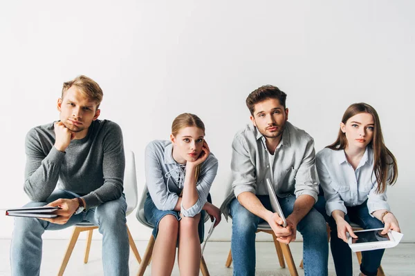 Group of young candidates with resume and gadgets looking at camera in office — Stock Photo