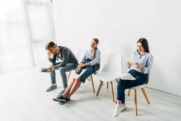 Hombre y mujeres cansados esperando entrevista de trabajo en la oficina - foto de stock