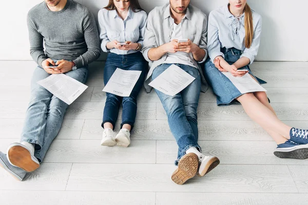 Cropped view of employees with resume using smartphones on floor — Stock Photo