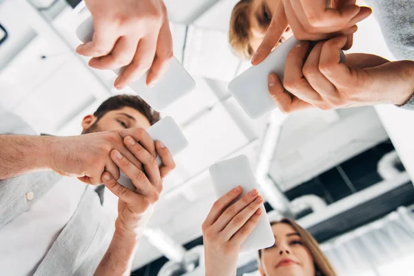 Vue du bas des jeunes utilisant des smartphones au bureau — Photo de stock