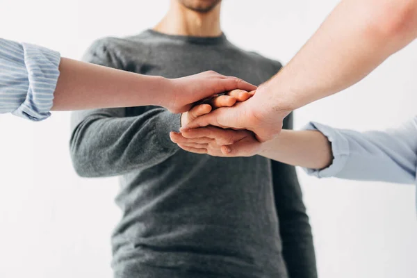 Cropped view of coworkers holding hands in office — Stock Photo