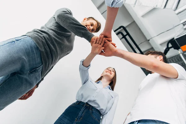 Low angle view of smiling coworkers holding hands in office — Stock Photo