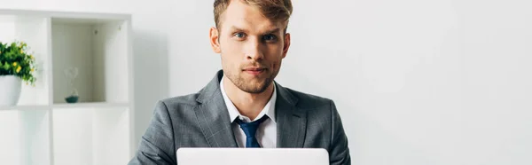 Panoramic shot of recruiter in suit looking at camera in office — Stock Photo